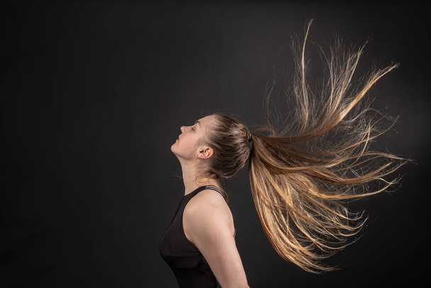 The girl in the shampoo commercial with her hair on black background - Foto, Bild