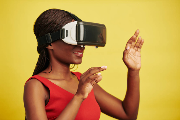 Portrait studio horizontal de femme noire portant un casque VR obtenant de nouvelles impressions, fond jaune
 - Photo, image