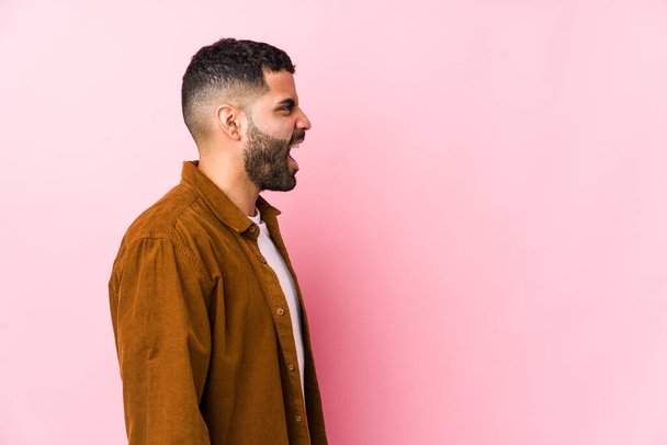 Young latin man against a pink background isolated shouting towards a copy space - Photo, Image