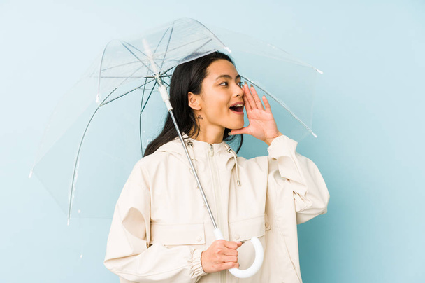 Joven mujer china sosteniendo un paraguas aislado alegre y confiado mostrando gesto ok
. - Foto, Imagen