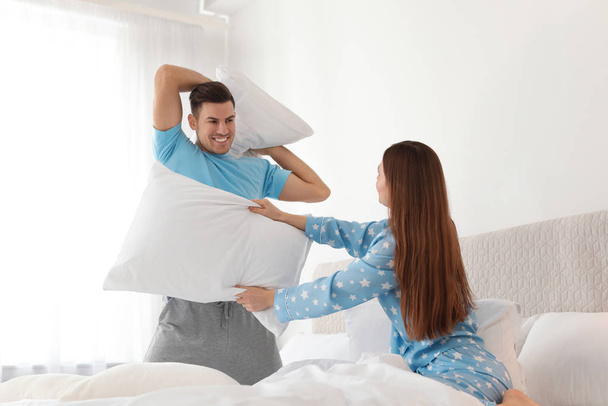 Happy couple having pillow fight in bedroom - Photo, image