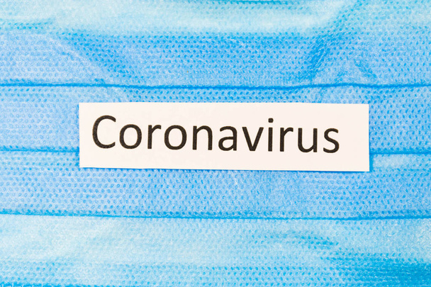 Защитная маска для лица синим на белом фоне от коронавируса с соответствующей надписью
 - Фото, изображение