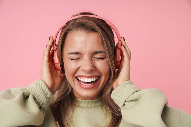 Portrait of blonde excited woman using headphones and laughing - Fotó, kép