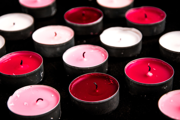 Набор розовых чайных свечей, лежащих на черном фоне
. - Фото, изображение