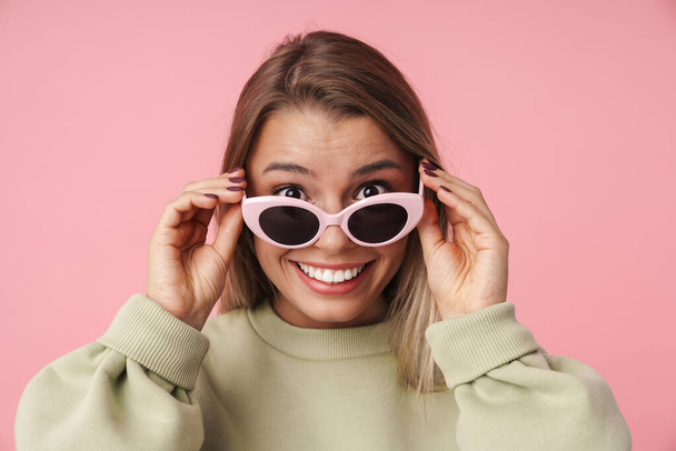 Portrait of smiling woman holding sunglasses and looking at camera - Фото, зображення