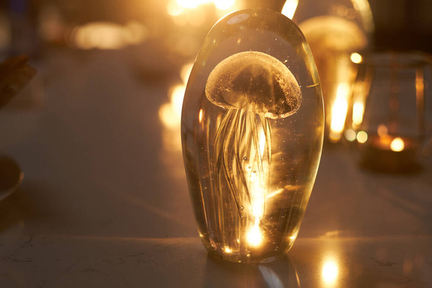 Conceptual jellyfish incluse ozdoba stojąca na stole oświetlonym światłem słonecznym w przytulnej kawiarni - Zdjęcie, obraz