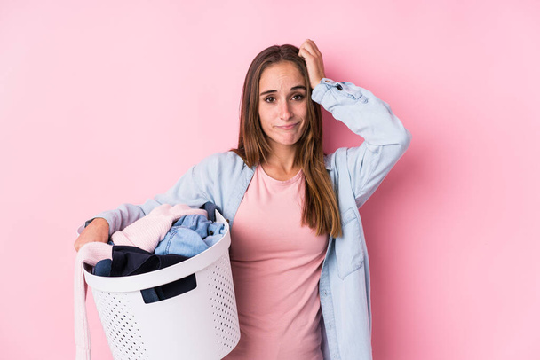 Young caucasian woman picking up dirty clothes isolated being shocked, she has remembered important meeting. - Foto, imagen