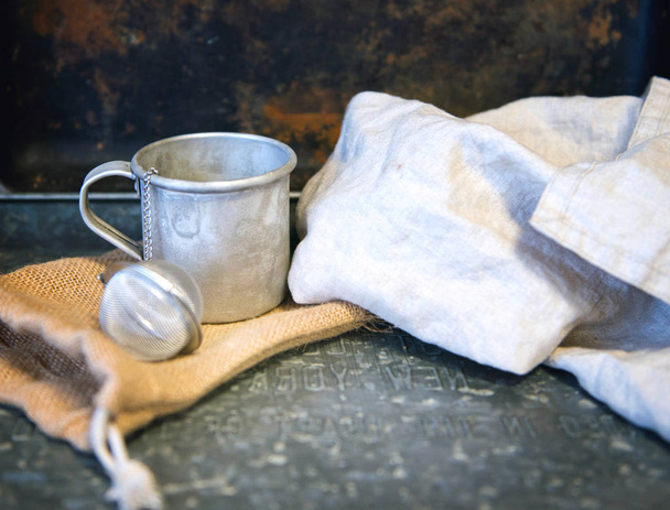 Xícara de chá de metal com ovo de chá atrás da toalha branca de algodão. estilo vintage rústico
 - Foto, Imagem
