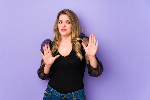 Young caucasian woman isolated on purple background rejecting someone showing a gesture of disgust. - Photo, Image