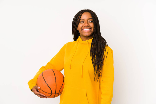 Joven mujer afroamericana jugando baloncesto aislado mira a un lado sonriente, alegre y agradable
. - Foto, imagen