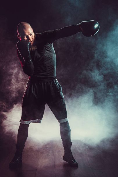 Sportsman boxer fighting on black background with smoke. Boxing sport concept - Фото, зображення