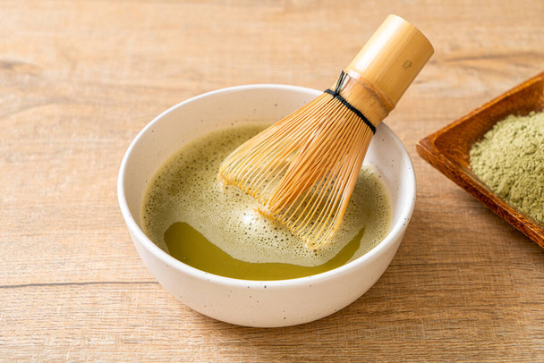hot matcha green tea cup with green tea powder and whisk - Foto, Bild