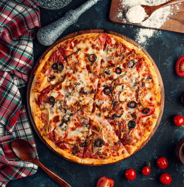 Top view of mixed pizza with tomato, black olive and melted cheese - Foto, afbeelding