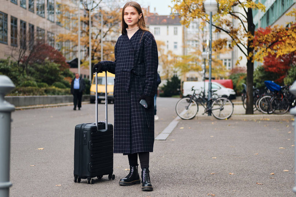 Schöne stilvolle Mädchen mit Koffer wartet Taxi in der Nähe Straße auf gemütliche Stadtstraße - Foto, Bild