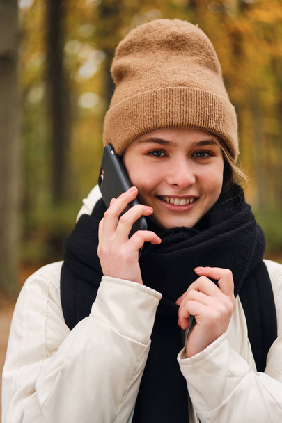 Retrato de chica alegre hablando en el teléfono celular mirando alegremente en la cámara al aire libre
 - Foto, Imagen