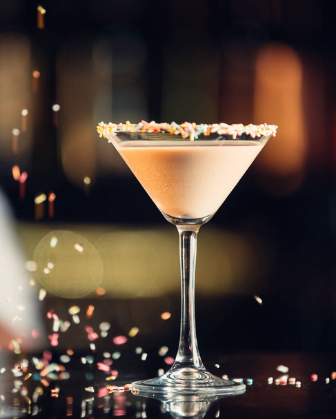 Zblízka ledový nápoj ve sklenici martini zdobené barevnými postřikovači - Fotografie, Obrázek