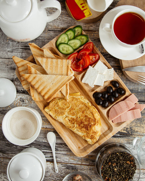 top view of breakfast setup with omelet toast cucumber tomato cheese olive - Foto, afbeelding