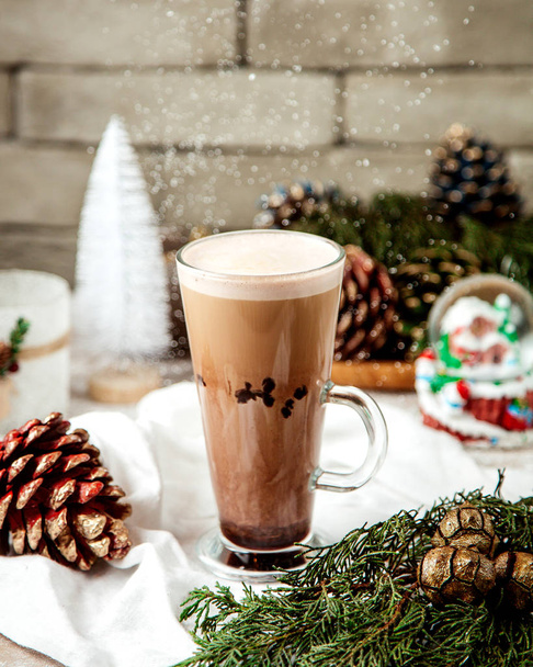 a cup of latte next to christmas decorations - Foto, Imagen