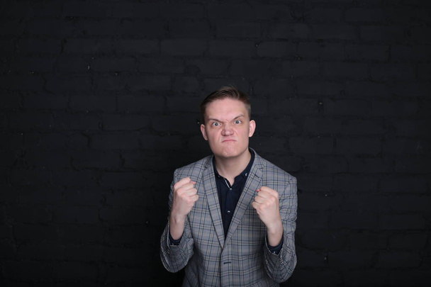 πορτρέτο συναισθηματικό κομψό νεαρός άνδρας σε ένα σακάκι και πουκάμισο σε σκούρο φόντο - Φωτογραφία, εικόνα