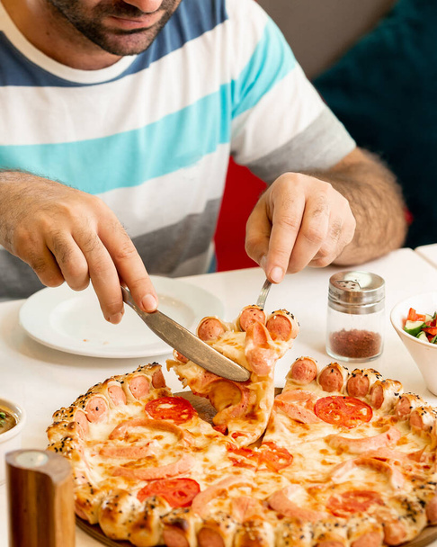 man taking a slice from sausage pizza - Foto, imagen