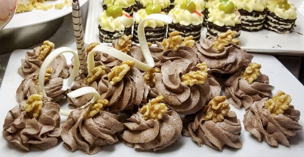 Tortas de galletas espolvoreadas con miga de nuez y decoradas con crema de chocolate están en una bandeja blanca vintage
 - Foto, imagen