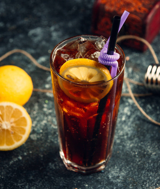 A glass of coca-cola with ice cubes and lemon slice in gray background - Foto, afbeelding