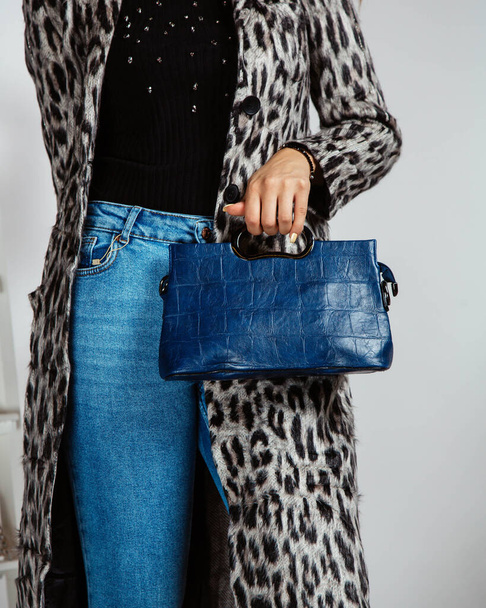 woman in jeans, black top and leopard print cardigan holding navy blue bag - Foto, imagen
