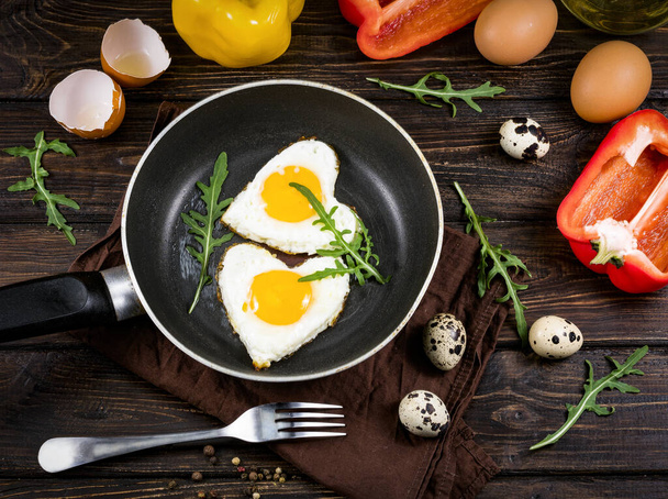 fried eggs on a skillet on a wooden background - Foto, afbeelding