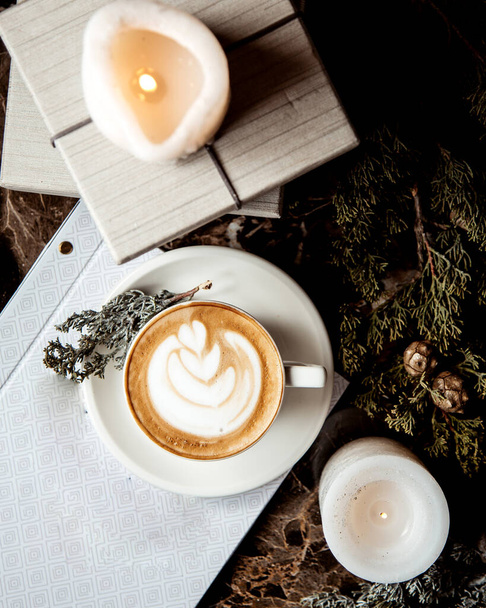 a cup of cappuccino and white candles - Фото, изображение