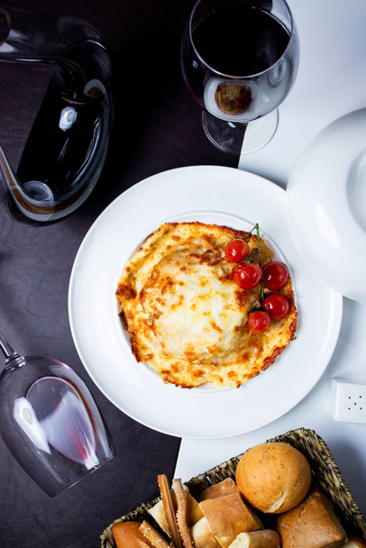 top view of roasted dish covered with melted cheese garnished with cherry tomato - Valokuva, kuva
