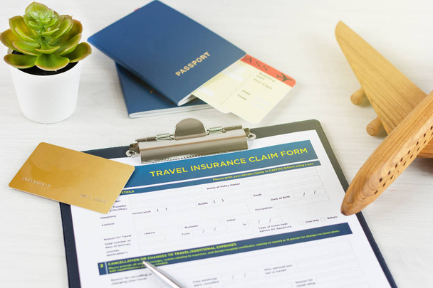 Travel insurance policy claim form with a boarding pass and passport on white wooden table. - Photo, Image