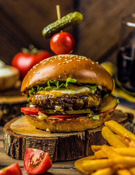 гамбургер из говядины с салатом, маринованный огурец, помидор, подается с картошкой фри
 - Фото, изображение