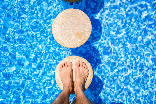 A vakációsnak a medencében pihentető lába. - Fotó, kép