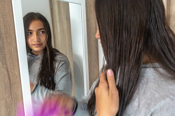 Teen combing her hair in front of the mirror - Photo, Image