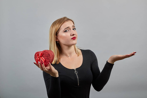 mulher feliz segurando uma caixa de presente em forma de coração vermelho em sua mão, palma para cima
 - Foto, Imagem