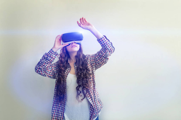 Sonríe mujer joven usando realidad virtual gafas VR casco auriculares sobre fondo blanco. Smartphone con gafas de realidad virtual. Tecnología, simulación, alta tecnología, concepto de videojuego. - Foto, Imagen