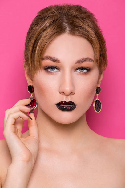 A beautiful young girl of European appearance with beautiful make-up on a pink background. Beauty Shooting - Foto, Imagen