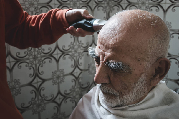 80χρονος κουρεύεται από τον εγγονό του στο παλιό, εκλεκτό μπάνιο. - Φωτογραφία, εικόνα