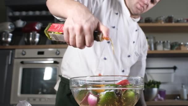 Koch in der modernen Küche des Restaurants gießt Olivenöl aus einer Flasche mit frischem geschnittenem Gemüse. Gegrilltes Gemüse kochen. Das Essen ist Gourmet. Leckeres Mittagessen. Zutaten für den Grill zubereiten - Filmmaterial, Video