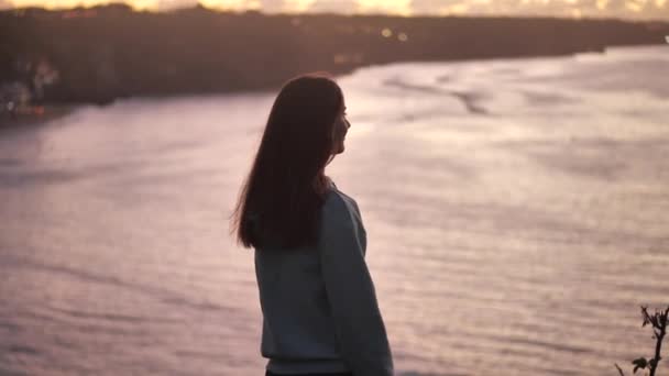 portrait en gros plan de belle jeune femme levant les bras avec le vent soufflant cheveux profiter paisible bord de mer au coucher du soleil 4k
 - Séquence, vidéo