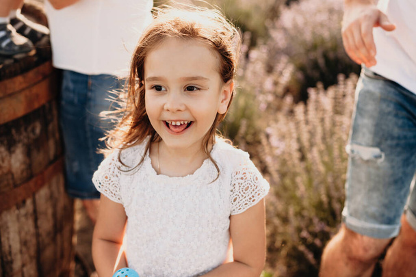 Egy bájos kislány pózol a levendulamezőn, boldogan mosolyog, és az örömöt sok érzelem veszi körül. - Fotó, kép
