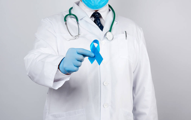 male doctor in a white coat and tie stands and holds a blue silk - 写真・画像