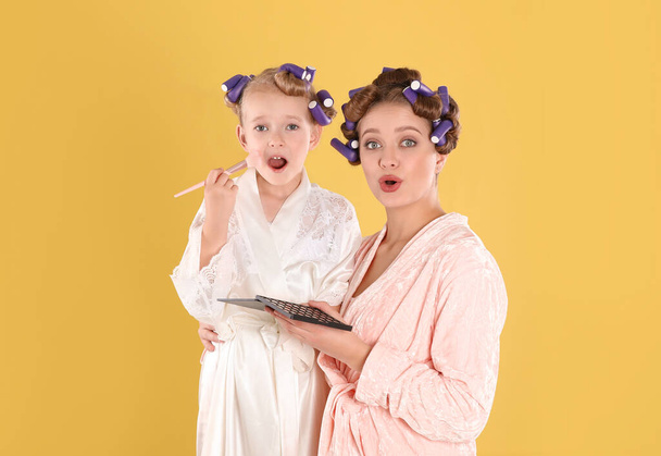 Emotional daughter and mother with cosmetic on yellow background - Foto, afbeelding