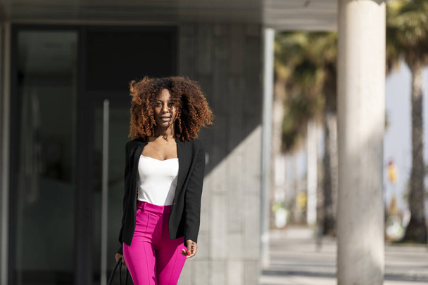 Retrato de uma bela mulher afro-americana de pé na rua em um dia ensolarado
 - Foto, Imagem