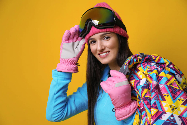 Woman wearing stylish winter sport clothes on yellow background - Foto, imagen