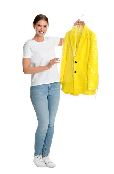 Young woman holding hanger with jacket in plastic bag on white b - Foto, Imagen