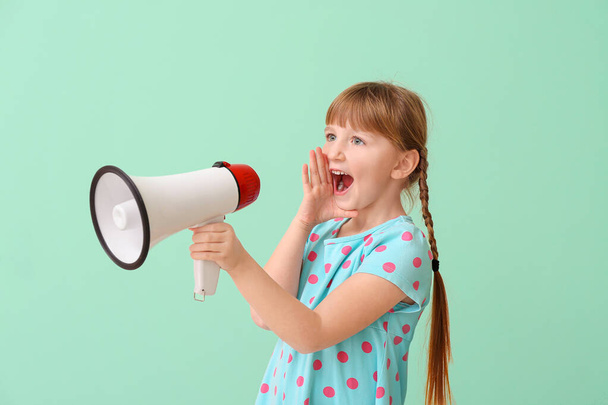 Cute little girl with megaphone on color background - Foto, afbeelding