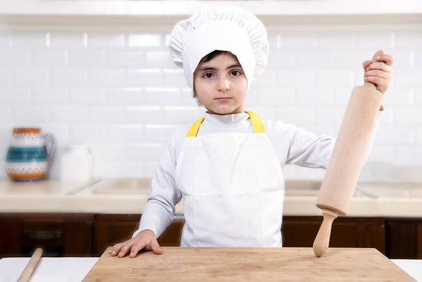 παιδί ντυμένο σεφ με πλάστη στο χέρι  - Φωτογραφία, εικόνα