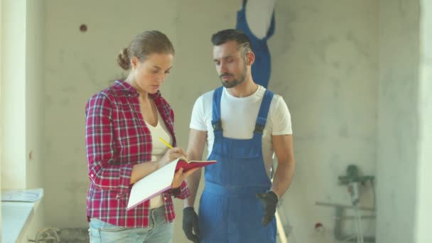 Woman talks with builder and makes notes - Footage, Video