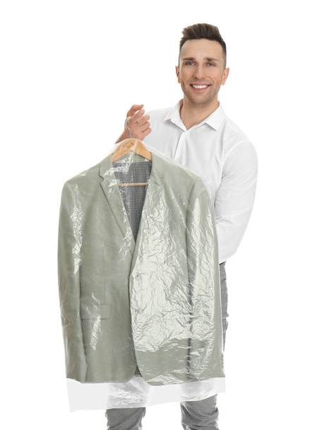 Man holding hanger with jacket in plastic bag on white background. Dry-cleaning service - Fotó, kép